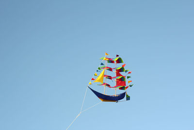 Low angle view of balloons flying against clear blue sky