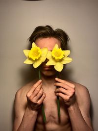 Close-up of hand holding yellow flowers over white background