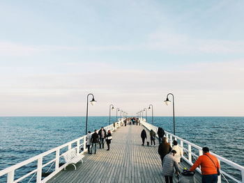 Rear view of people by sea against sky