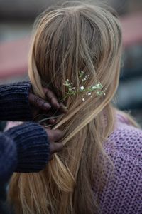 Cropped hands of woman wearing flowers in friend hair