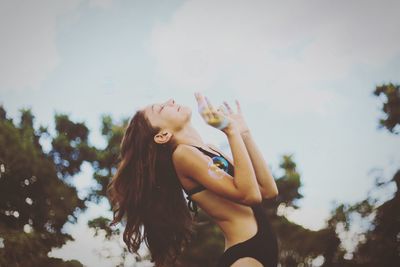 Side view of happy young woman with eyes closed against sky