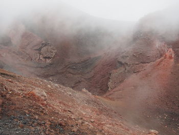 Scenic view of rocky mountains in foggy weather