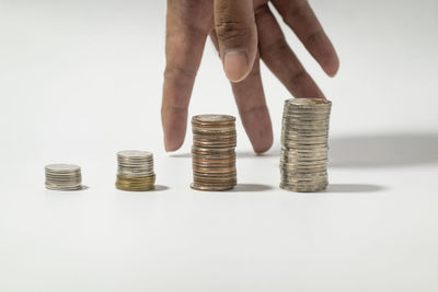 Close-up of hand holding stack of objects over white background