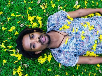 High angle portrait of young man lying on grassy field