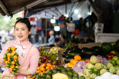Woman with vietnam culture traditional dress standing at fruit market in hoi an.