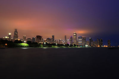 Illuminated buildings in city against sky at night