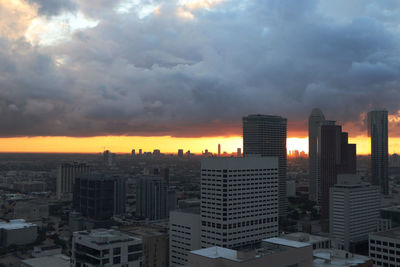 Modern buildings in city against sky during sunset