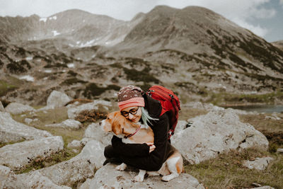 Girl with dog sitting on rock