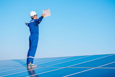 Man standing on mobile phone against clear blue sky