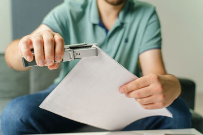 Midsection of woman holding paper while sitting on floor