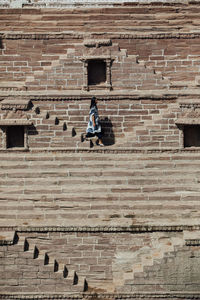 Side view of woman on staircase against brick wall