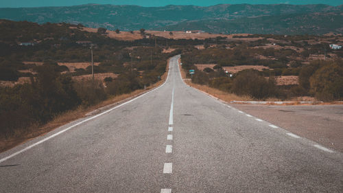 Empty road amidst landscape against sky