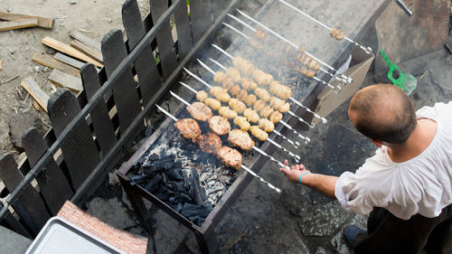 High angle view of man roasting meat on barbeque