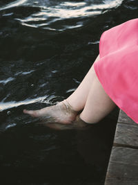 Low section of woman sitting with feet in water