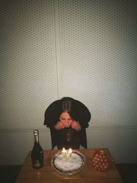 Mid adult woman with chocolate cake on table against wall at home