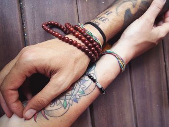 Cropped hands of couple with tattoo on table