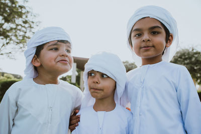 Cute brothers wearing traditional clothing standing in park