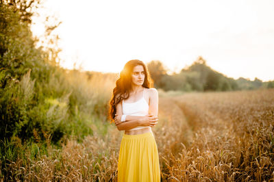 A girl runs through a field with spikelets against the background of the setting sun