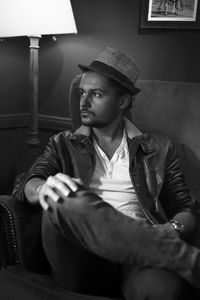 Thoughtful young man sitting on armchair at home