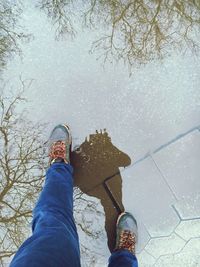 Reflection of man in puddle while standing on paving stone