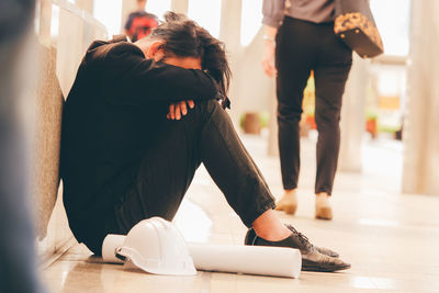 Full length of tensed man sitting on floor