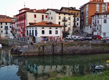 Houses by lake against buildings in city