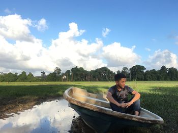 Man sitting in boat against sky