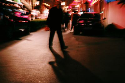 Low section of woman walking on illuminated city at night