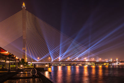 Illuminated rama viii bridge over river against sky at night in city