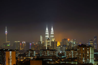 Illuminated modern cityscape against sky at night