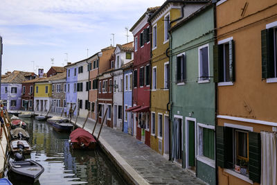 Boats moored in canal amidst buildings in city