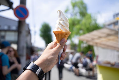 Ice cream in the hand held up in the sky on street.