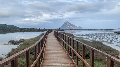 Footbridge over lake against sky