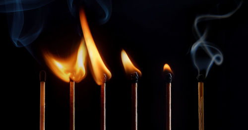 Close-up of burning candles against black background