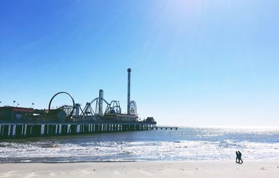 Pier and amusement park at beach against sky