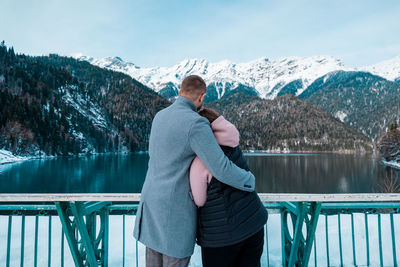 Couple hugging and looking at the lake in the mountains