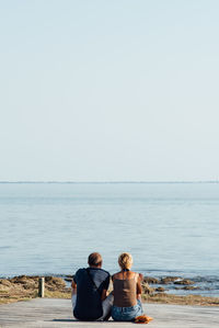 Rear view of couple looking at sea against clear sky