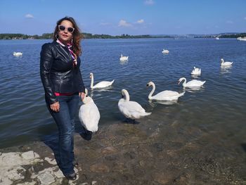 Portrait of woman standing in lake by swans