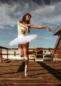 Full length of young woman sitting on boardwalk