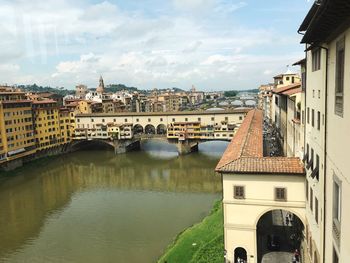 Arch bridge over river against buildings in city