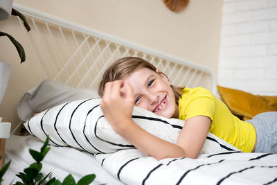 A blond boy in a yellow t-shirt lies on the bed having fun at home happy kids childhood