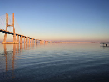 Suspension bridge over sea against clear sky