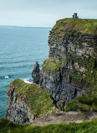 Scenic view of cliff by sea against sky