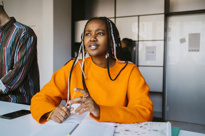 Thoughtful young woman with braided hair sitting at university