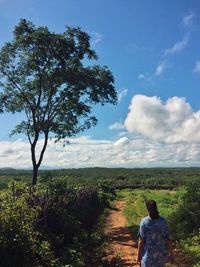 Rear view of man and woman by flower tree against sky