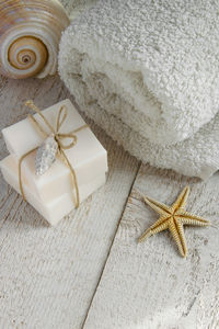 High angle view of soap bars with rolled up towel and starfish on wooden table