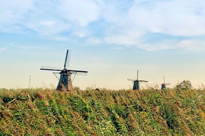 Windmills on field against sky