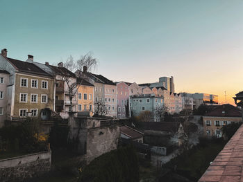 Buildings in city against clear sky during sunset