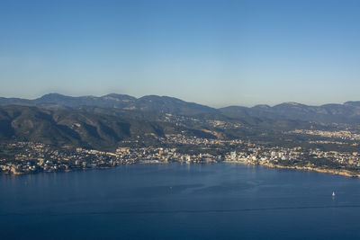 Aerial view of sea and mountains against clear blue sky