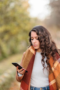 Young woman using mobile phone while standing outdoors